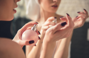 A woman holding onto a pink bottle of perfume